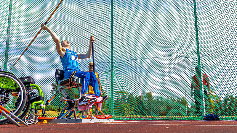 Henri Kössö heittämässä keihästä istuen.