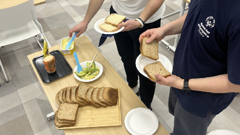 Joukkuelaisia kokoamassa tervellistä, ravitsevaa välipalaleipää.