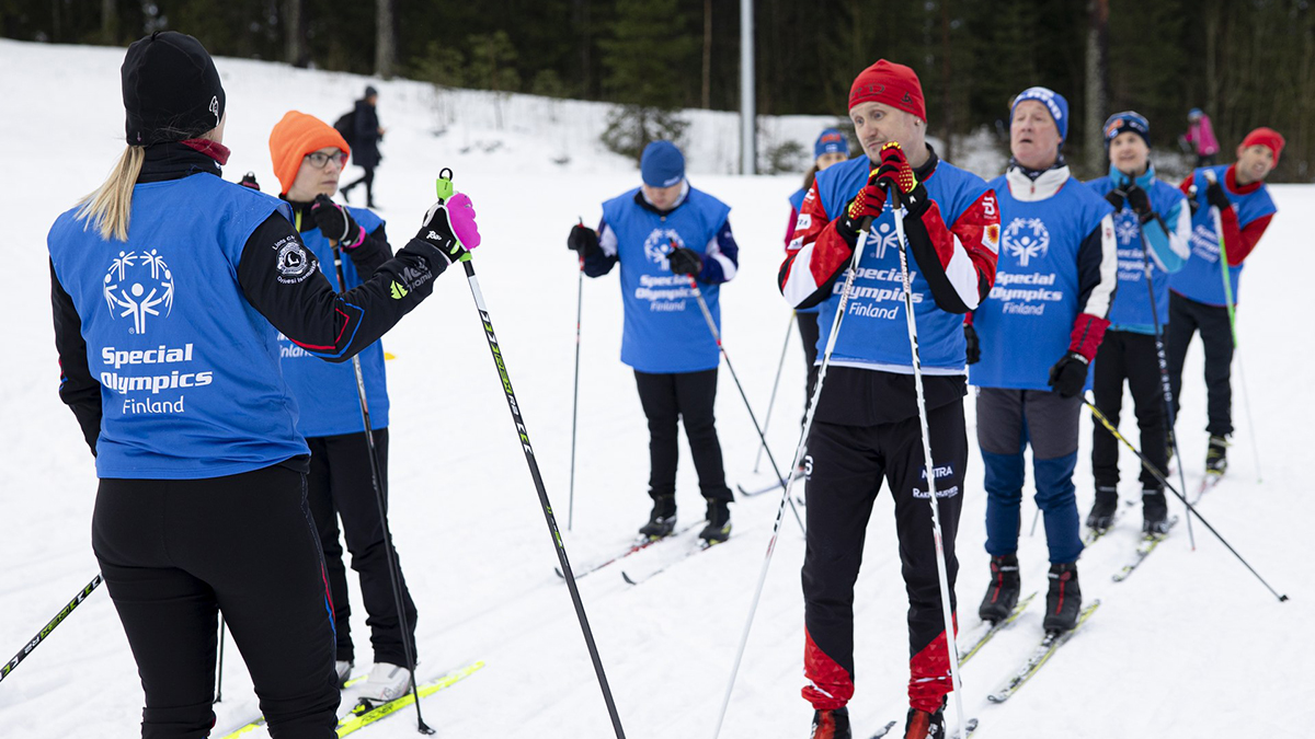 Sisujengin hiihtäjiä ladulla jonossa valmiina lähtöön, kuuntelemassa valmentajan ohjeistusta.